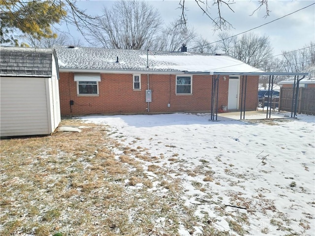 snow covered house featuring a storage unit