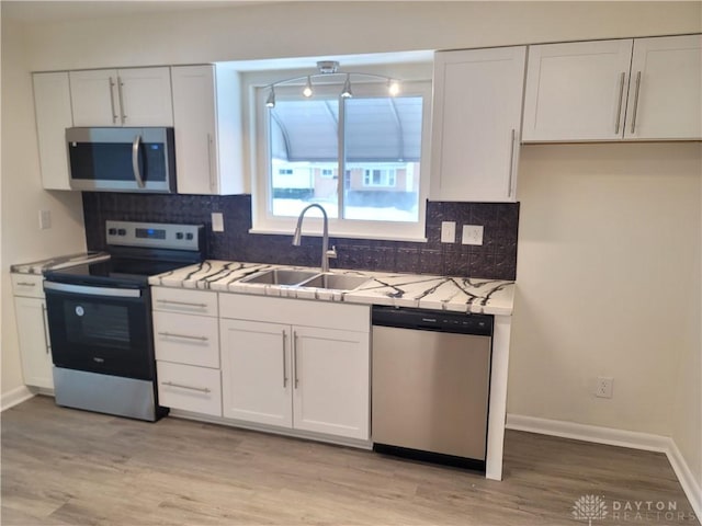 kitchen with light hardwood / wood-style floors, white cabinets, appliances with stainless steel finishes, and sink