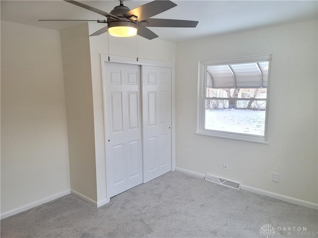 unfurnished bedroom with light carpet, a closet, and ceiling fan