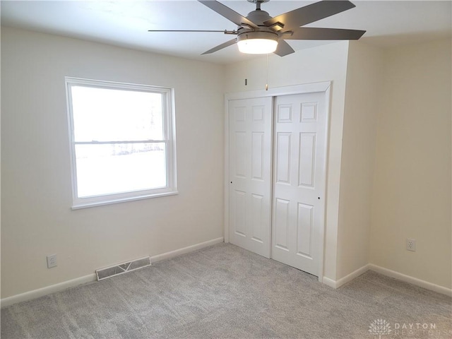 unfurnished bedroom with ceiling fan, a closet, and light carpet