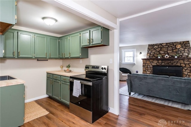 kitchen featuring electric stove, green cabinetry, a stone fireplace, and dark wood-type flooring