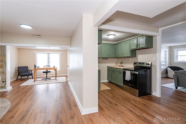 kitchen with green cabinetry, light hardwood / wood-style flooring, and stainless steel electric range