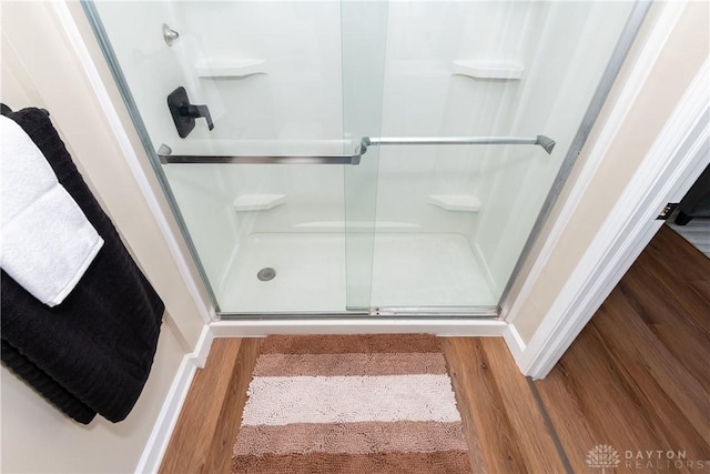 bathroom with hardwood / wood-style flooring and a shower with shower door