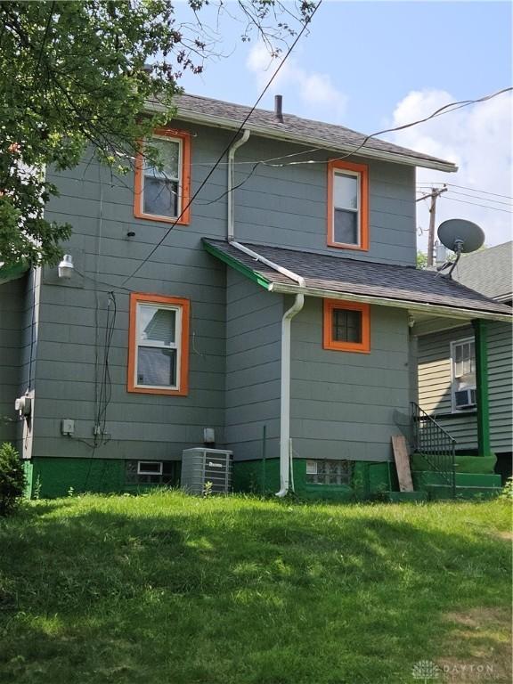 back of property featuring cooling unit, central AC, and a yard