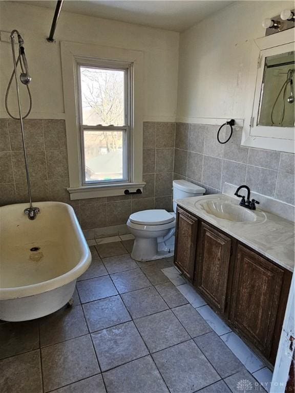 bathroom featuring tile patterned flooring, vanity, tile walls, toilet, and a washtub