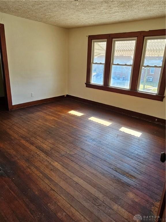 empty room featuring a textured ceiling and dark hardwood / wood-style floors