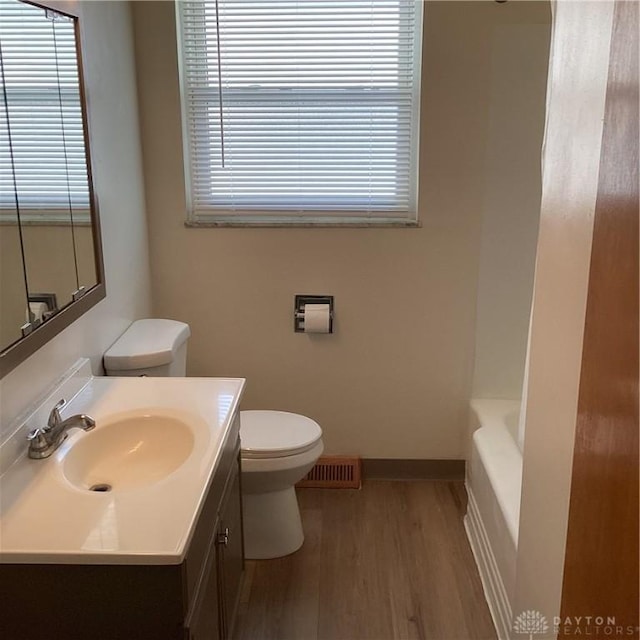 full bathroom with baseboards, visible vents, toilet, wood finished floors, and vanity