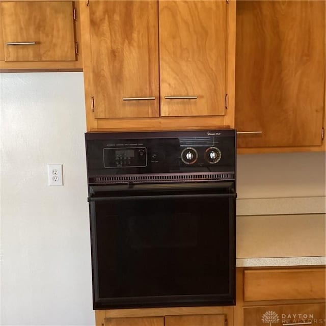 interior details with brown cabinets, light countertops, and black oven