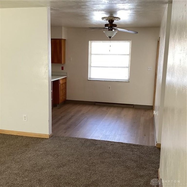 unfurnished room with light colored carpet, ceiling fan, light wood finished floors, and baseboards