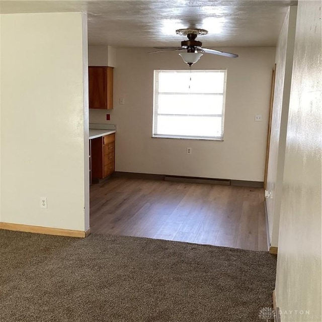 empty room with light carpet, ceiling fan, baseboards, and light wood-style flooring