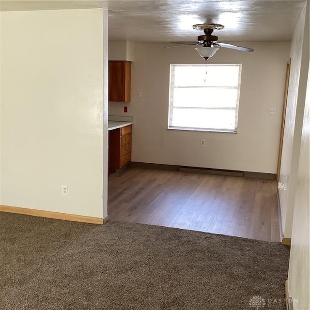 carpeted empty room with baseboards and a ceiling fan