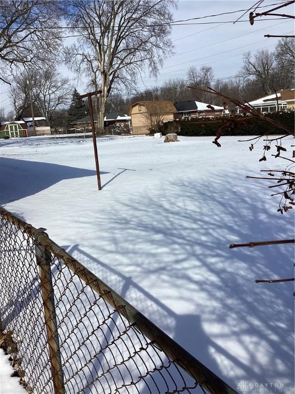 snowy yard featuring fence