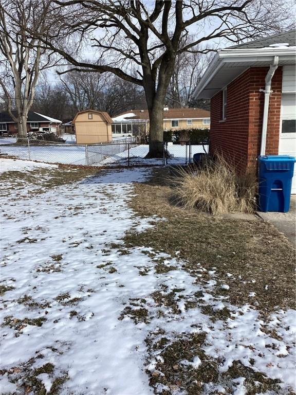 yard layered in snow with fence and a storage unit