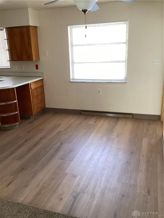 interior space featuring light wood-style floors, baseboards, and a ceiling fan