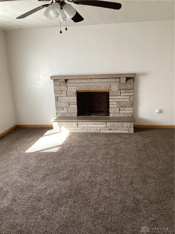 unfurnished living room with ceiling fan, carpet, a fireplace, and baseboards