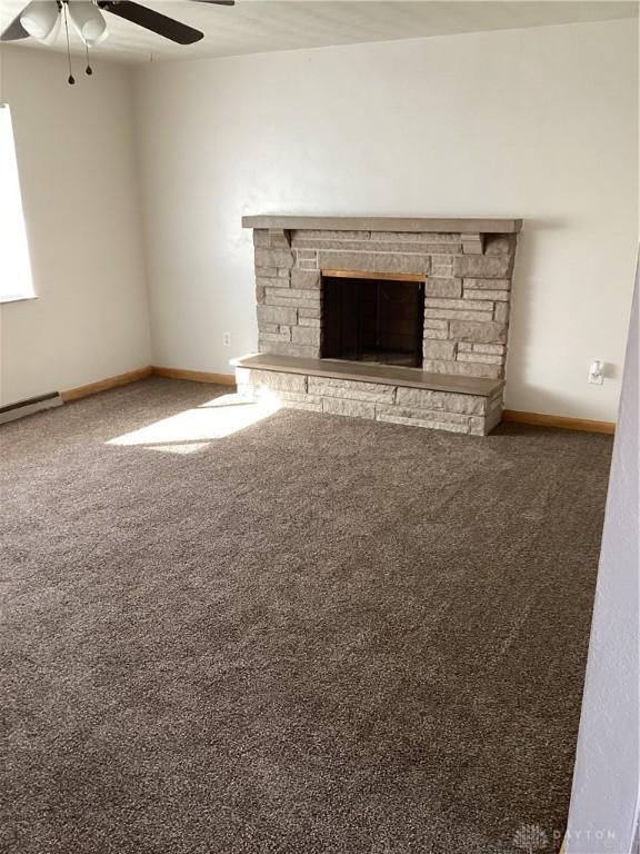 unfurnished living room featuring ceiling fan, carpet floors, a fireplace, and baseboards