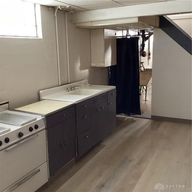 kitchen featuring electric range, white cabinetry, light countertops, and dark cabinetry