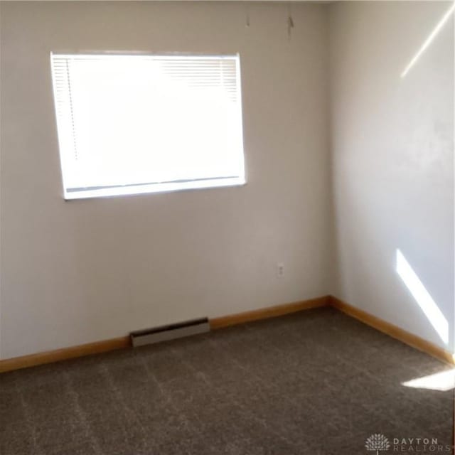 empty room featuring dark colored carpet, visible vents, and baseboards