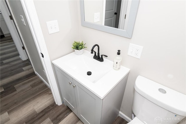 bathroom with hardwood / wood-style flooring, toilet, and vanity