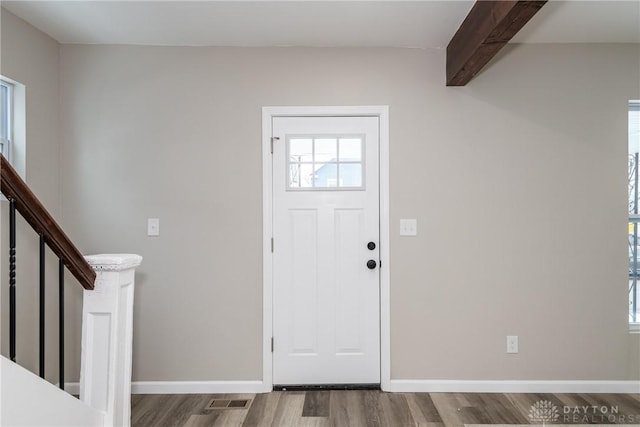 foyer entrance with beamed ceiling and hardwood / wood-style floors