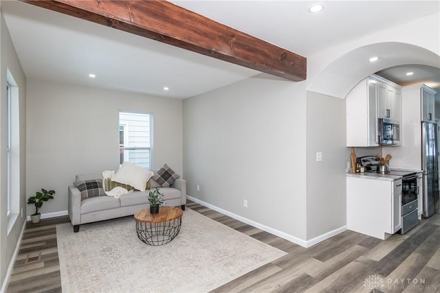 living room featuring beamed ceiling and dark wood-type flooring