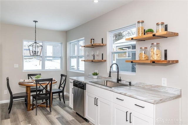 kitchen featuring pendant lighting, white cabinetry, sink, stainless steel dishwasher, and light hardwood / wood-style flooring