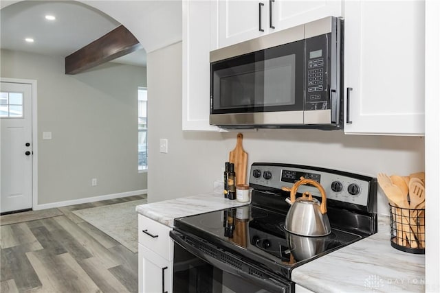 kitchen with range with electric cooktop, white cabinets, light hardwood / wood-style flooring, and light stone countertops