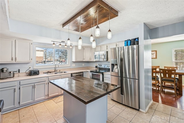 kitchen featuring sink, decorative light fixtures, light tile patterned floors, appliances with stainless steel finishes, and a kitchen island