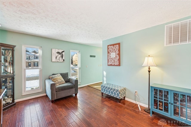 sitting room featuring dark wood-type flooring, plenty of natural light, and a textured ceiling