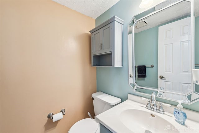 bathroom with vanity, toilet, and a textured ceiling