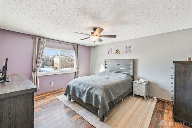 bedroom with ceiling fan, hardwood / wood-style floors, and a textured ceiling