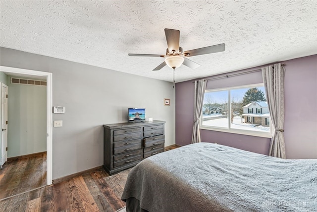 bedroom with a textured ceiling, dark hardwood / wood-style floors, and ceiling fan