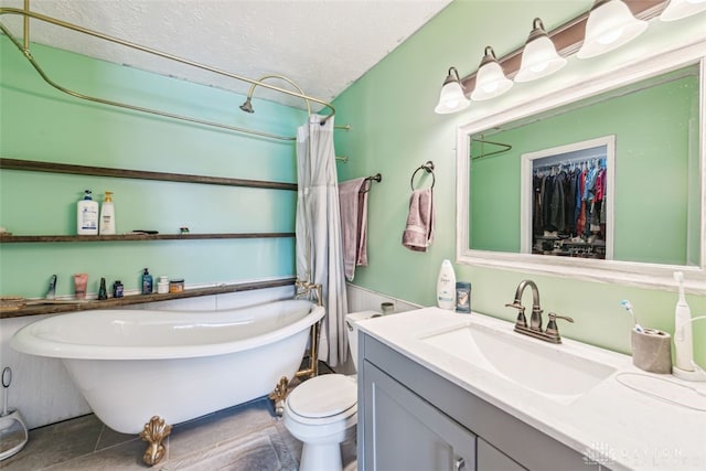 bathroom featuring vanity, a washtub, toilet, tile patterned floors, and a textured ceiling