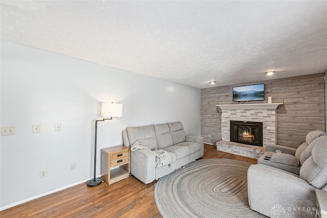 living room with light hardwood / wood-style flooring, wooden walls, and a textured ceiling