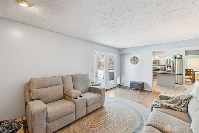 living room featuring a textured ceiling, light wood-type flooring, and french doors