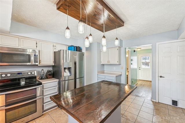 kitchen featuring a kitchen island, light tile patterned flooring, appliances with stainless steel finishes, and decorative light fixtures