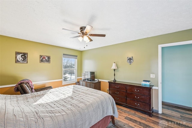 bedroom featuring dark wood-type flooring, a textured ceiling, and ceiling fan