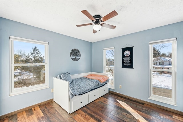 bedroom with multiple windows, dark wood-type flooring, and ceiling fan