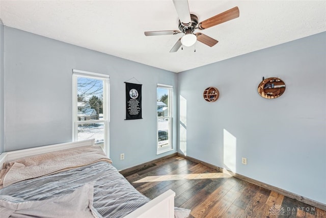 bedroom with ceiling fan, dark hardwood / wood-style floors, and multiple windows