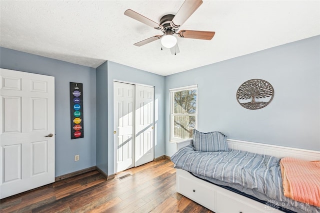 bedroom featuring dark hardwood / wood-style floors, a textured ceiling, ceiling fan, and a closet