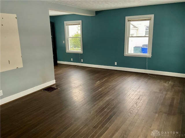 empty room featuring dark hardwood / wood-style floors and a textured ceiling