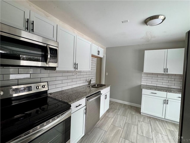 kitchen featuring white cabinetry, appliances with stainless steel finishes, dark stone countertops, and decorative backsplash