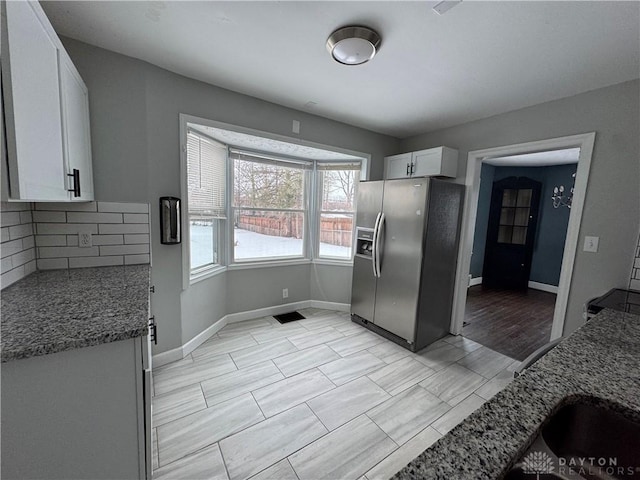 kitchen with stone countertops, stainless steel fridge, decorative backsplash, and white cabinets