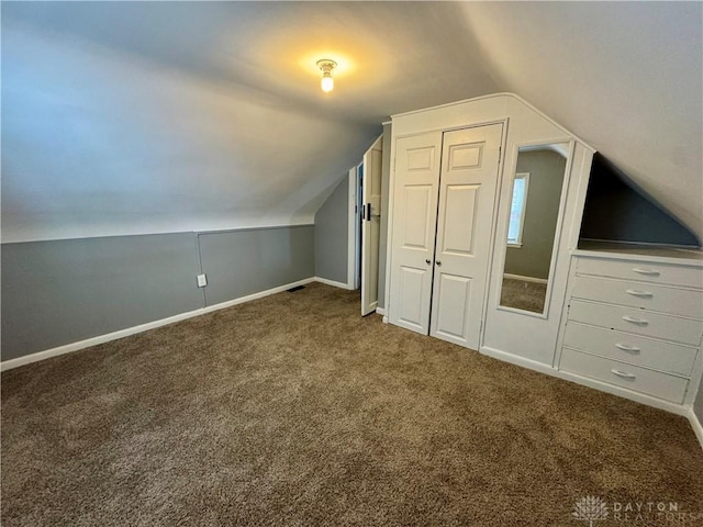 additional living space featuring vaulted ceiling and dark colored carpet