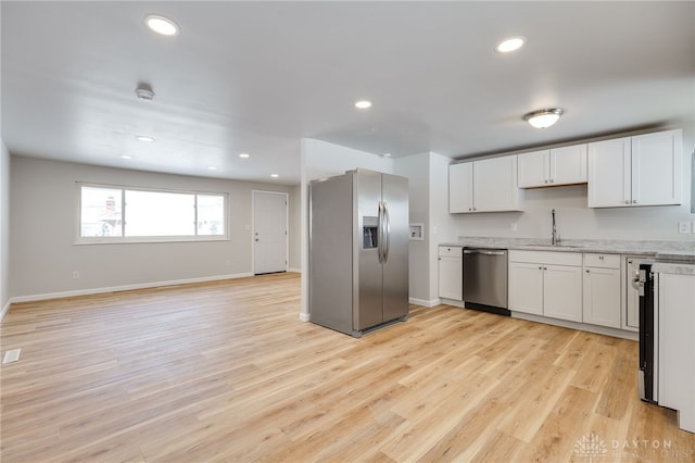 kitchen with white cabinetry, sink, stainless steel appliances, and light hardwood / wood-style floors