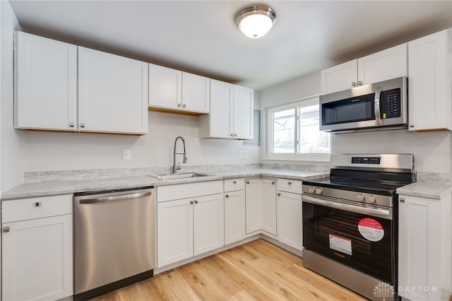 kitchen featuring white cabinetry, appliances with stainless steel finishes, sink, and light hardwood / wood-style floors