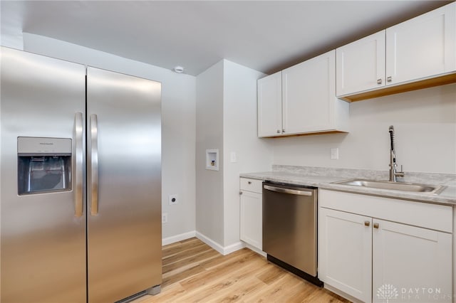 kitchen featuring stainless steel appliances, sink, light hardwood / wood-style flooring, and white cabinets