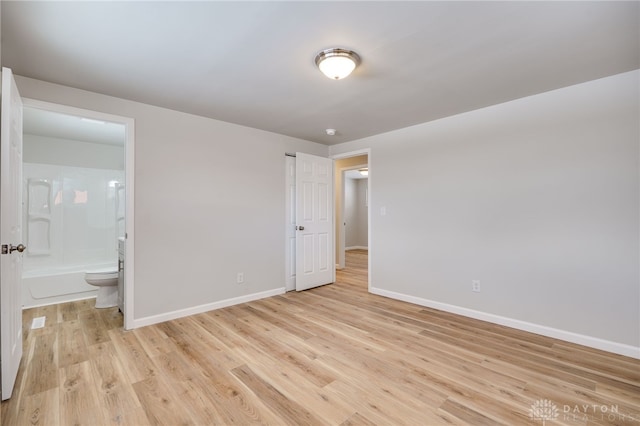 unfurnished bedroom with ensuite bathroom and light wood-type flooring