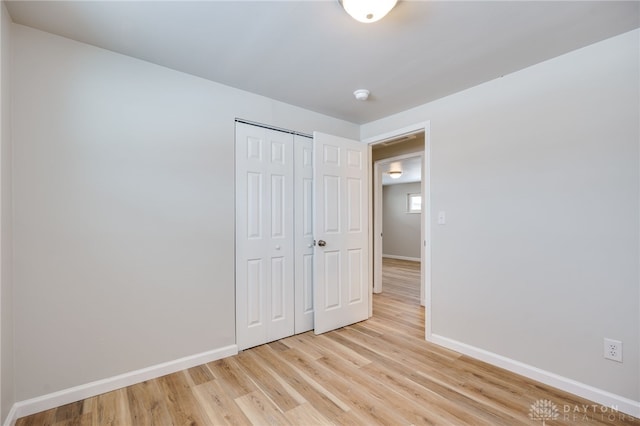 unfurnished bedroom with a closet and light wood-type flooring