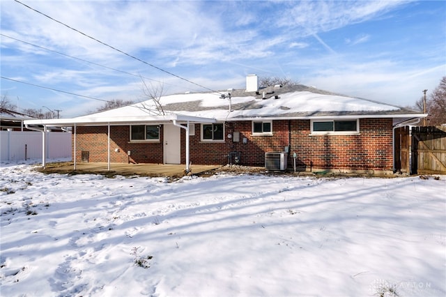 snow covered rear of property featuring cooling unit